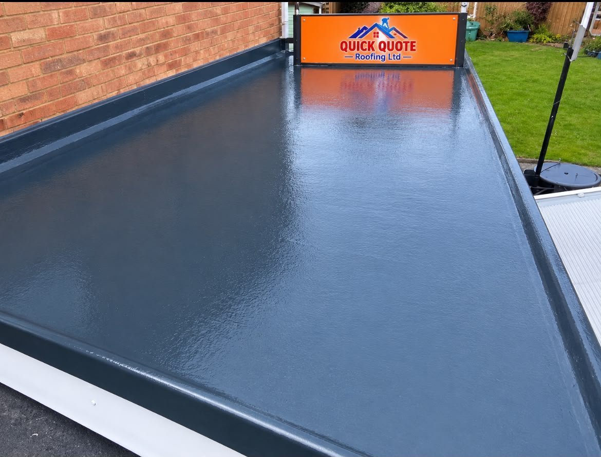 Flat roof with wet dark gray membrane surface, orange Quick Quote roofing sign, brick wall and green lawn visible