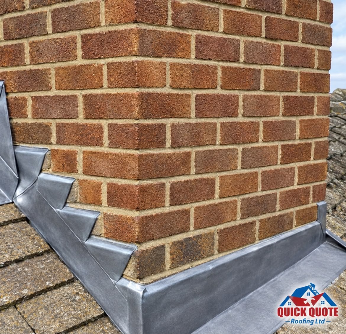 Brick chimney corner with metal flashing base on a roof, showing weathered red bricks and mortar joints